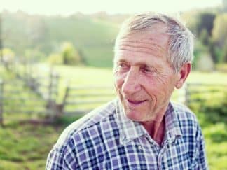 lose up of a man in a field smiling looking off into the distance